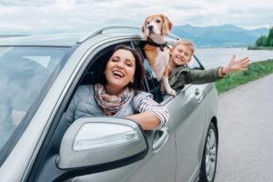 happy mother son and dog leaning out of car window