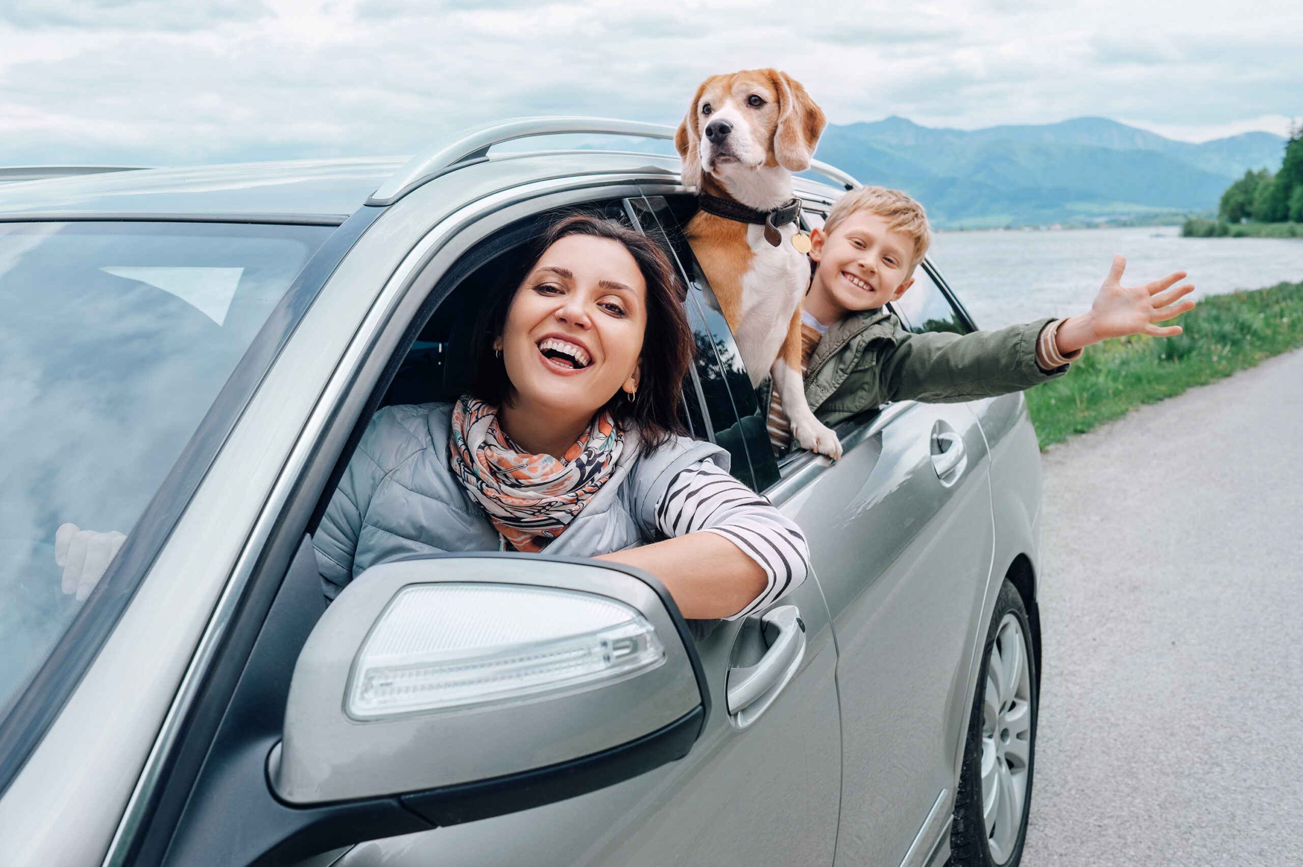 happy mother son and dog leaning out of car window
