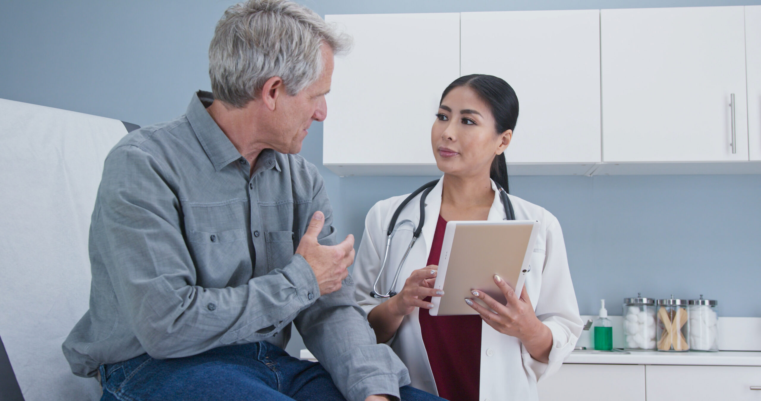 asian female doctor talking to older male patient