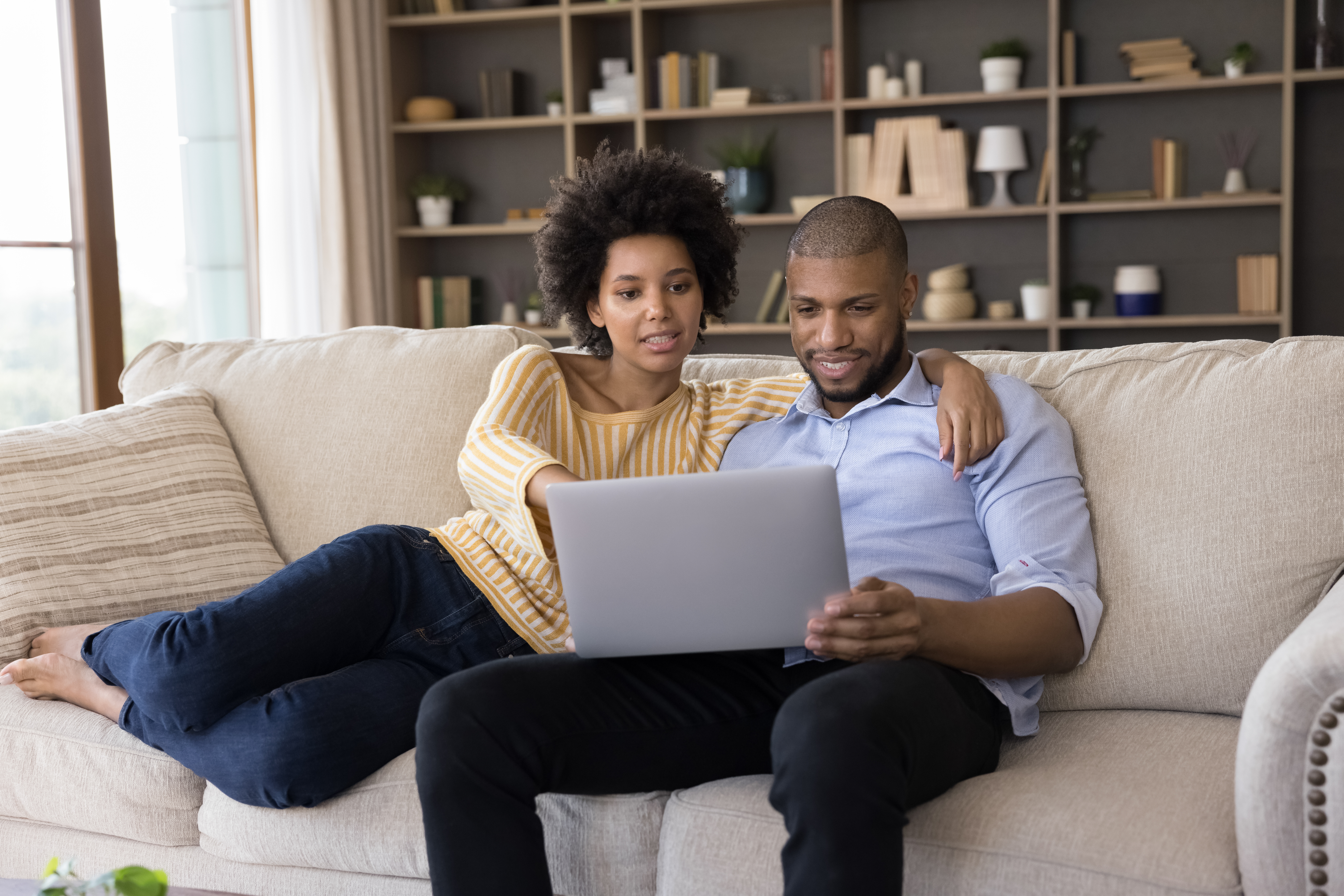 couple sitting on couch looking at laptop