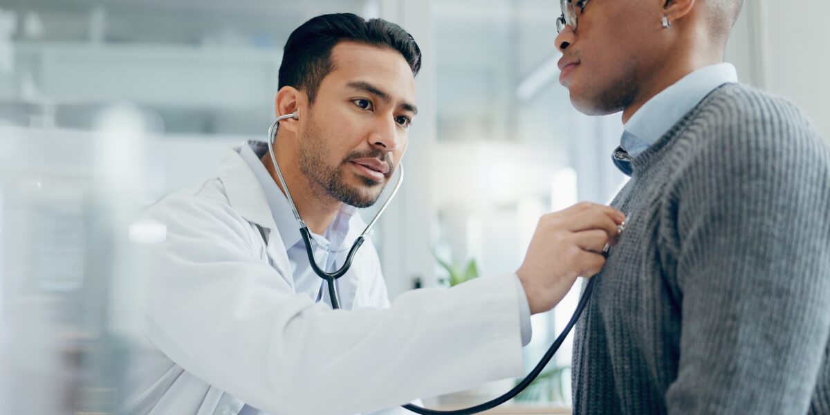 male doctor checking male patient heartbeat