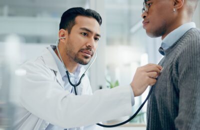 male doctor checking male patient heartbeat
