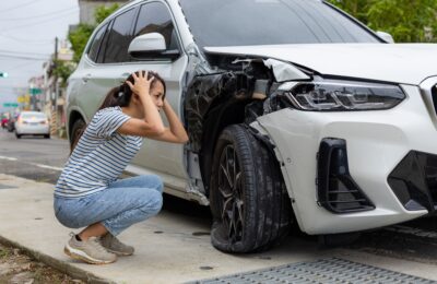frightened woman sits in front of crashed car