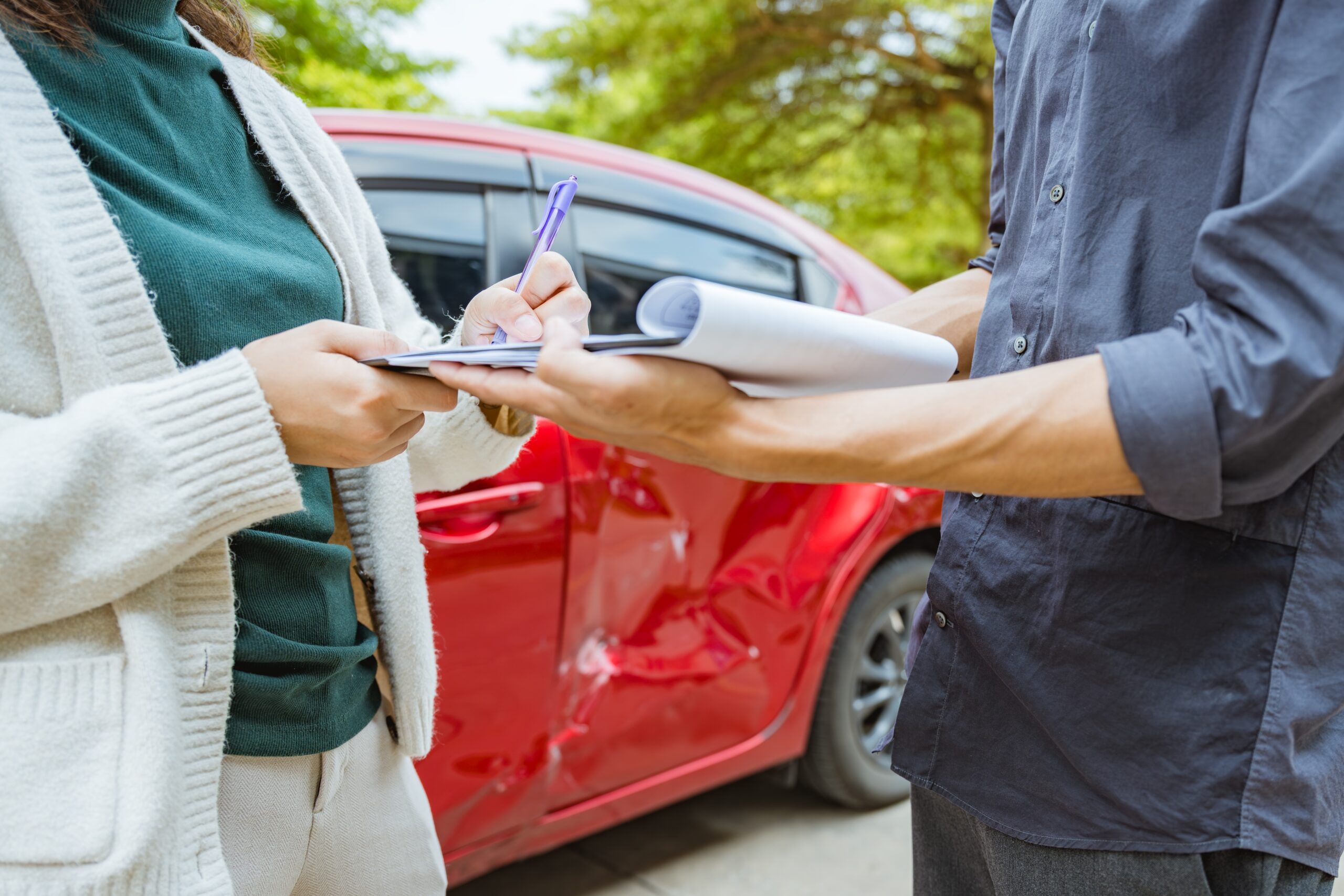 car crash with two people reviewing and signing documents