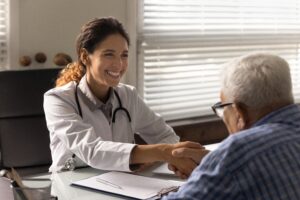 female physician shaking the hand of an old man across from her