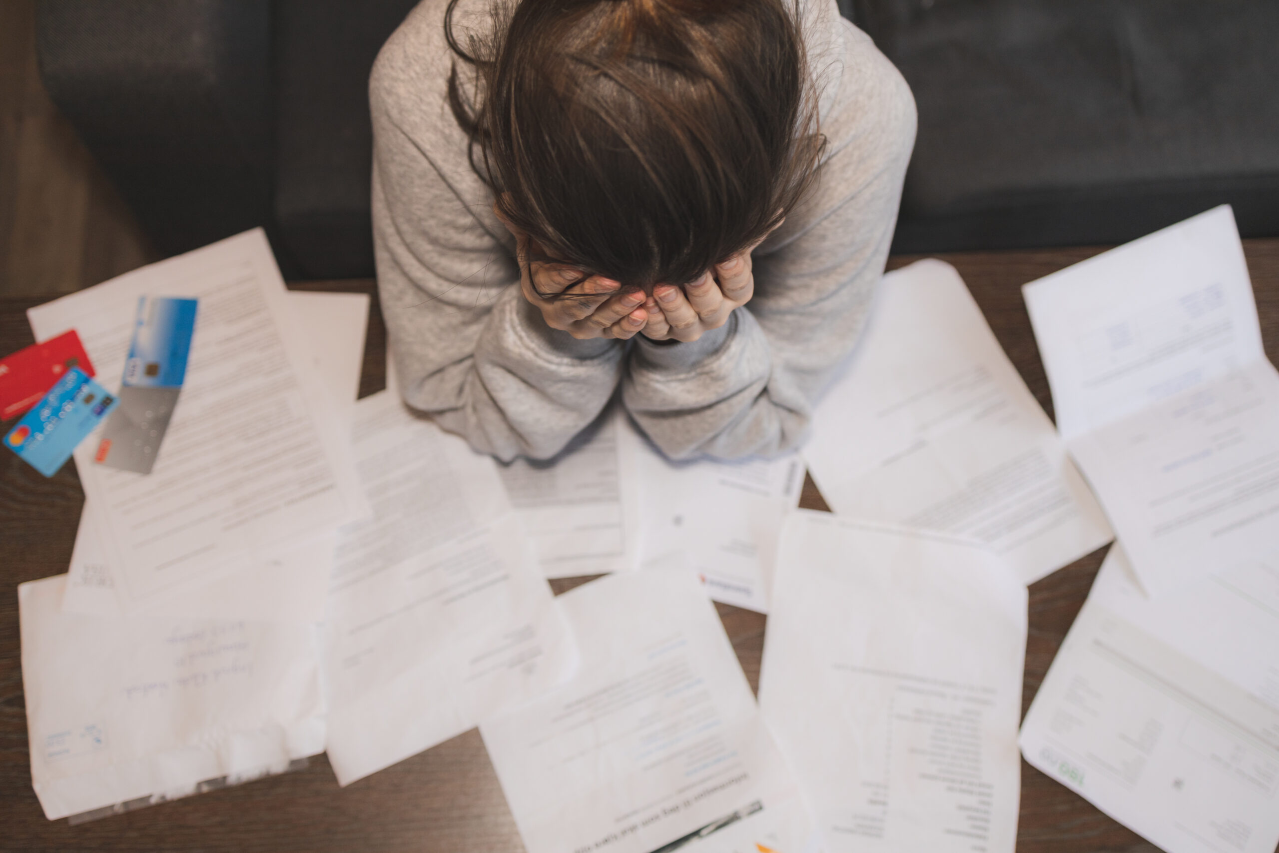 shocked and stressed young woman with papers spread across desk