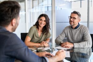 smiling couple meeting at desk having discussion with an agent