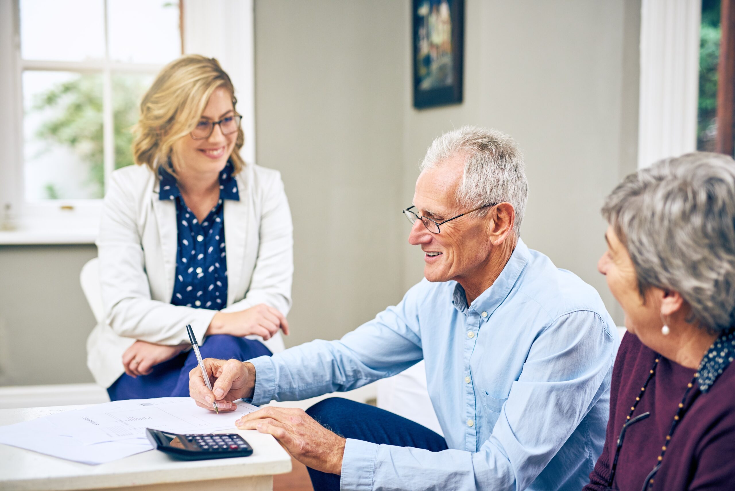 senior couple doing paperwork and meeting with younger female