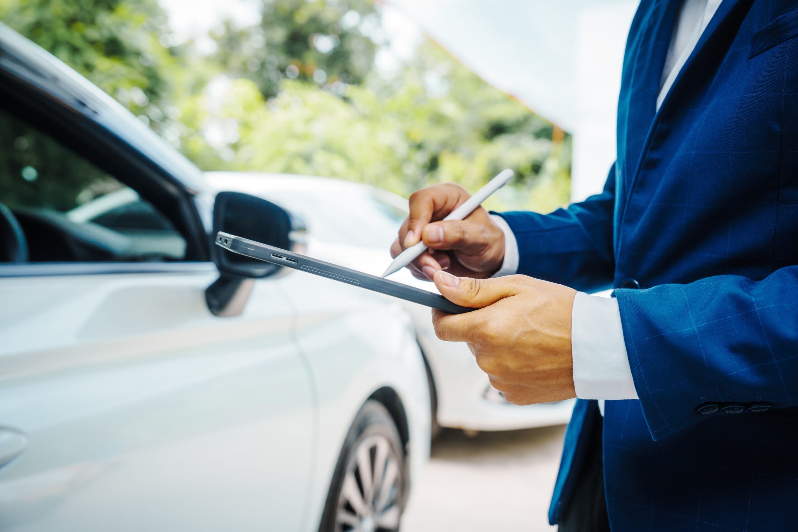 man in suit holding clipboard and pen assessing car