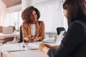 two young women discussing over paperwork