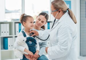 child and mother at exam with doctor using stethescope