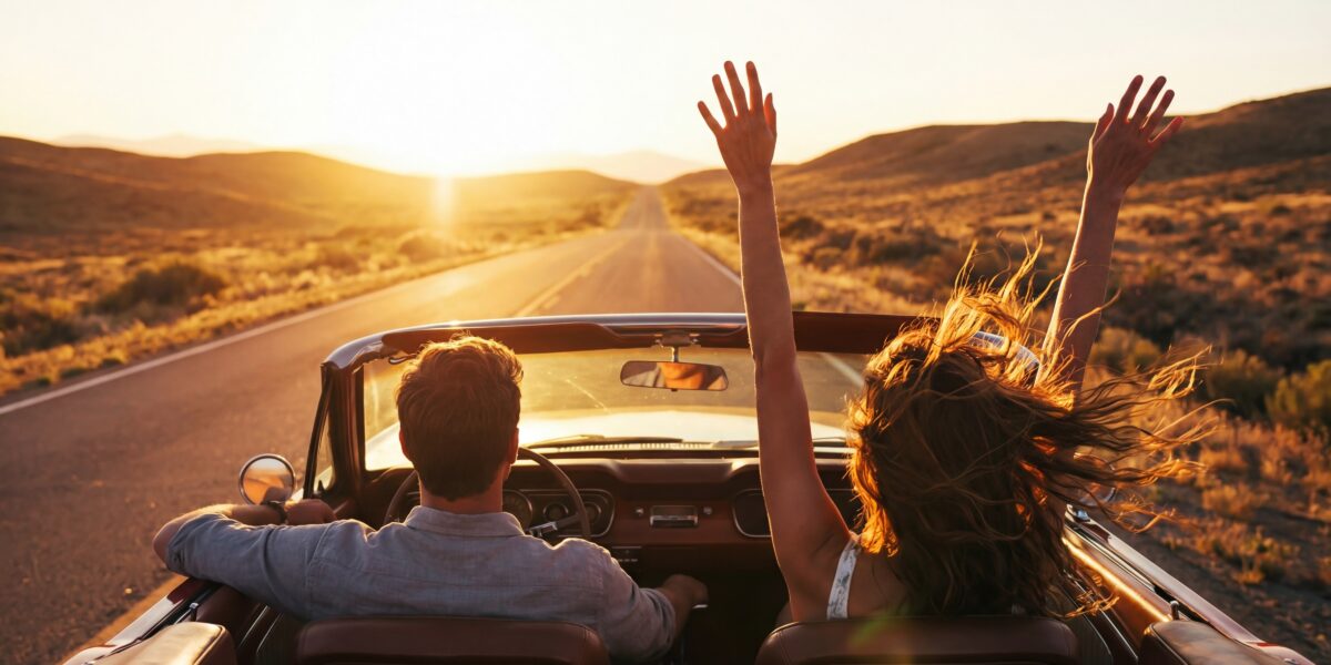 young couple driving convertible through desert