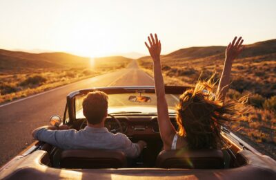 young couple driving convertible through desert